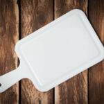 White Plastic cutting board isolated on wood background.